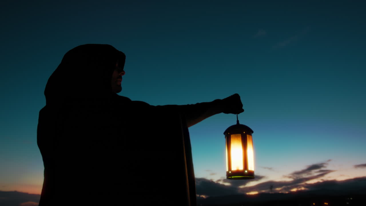 지혜로운 중세 마법사 의 실루 은 등불 을 들고 별 들 을 바라보고 있다