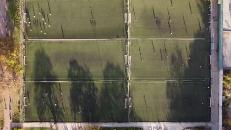 a stationary top-down aerial shot of football players playing football on six adjoined football fields at a time