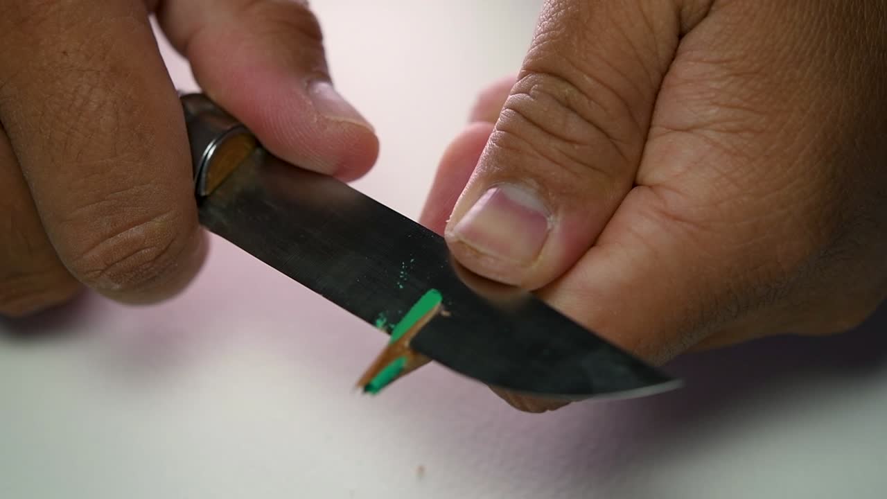 imágenes de manos afilando lentamente un lápiz y algunos lápices de colores con un cuchillo afilado