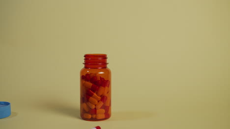 slow motion wide shot of a bottle of pills falling and landing, the lid pops off and a single pill bounces out