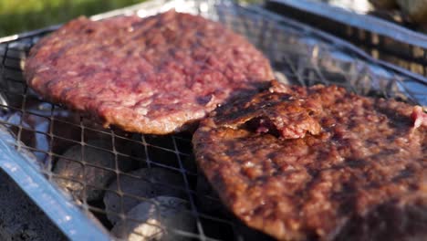 hamburguesas de ternera cocinando en una pequeña barbacoa desechable