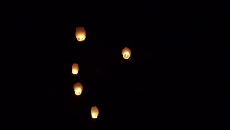 Multiple-sky-lanterns-glowing-in-the-dark-night-sky,-creating-a-serene-and-mystical-atmosphere