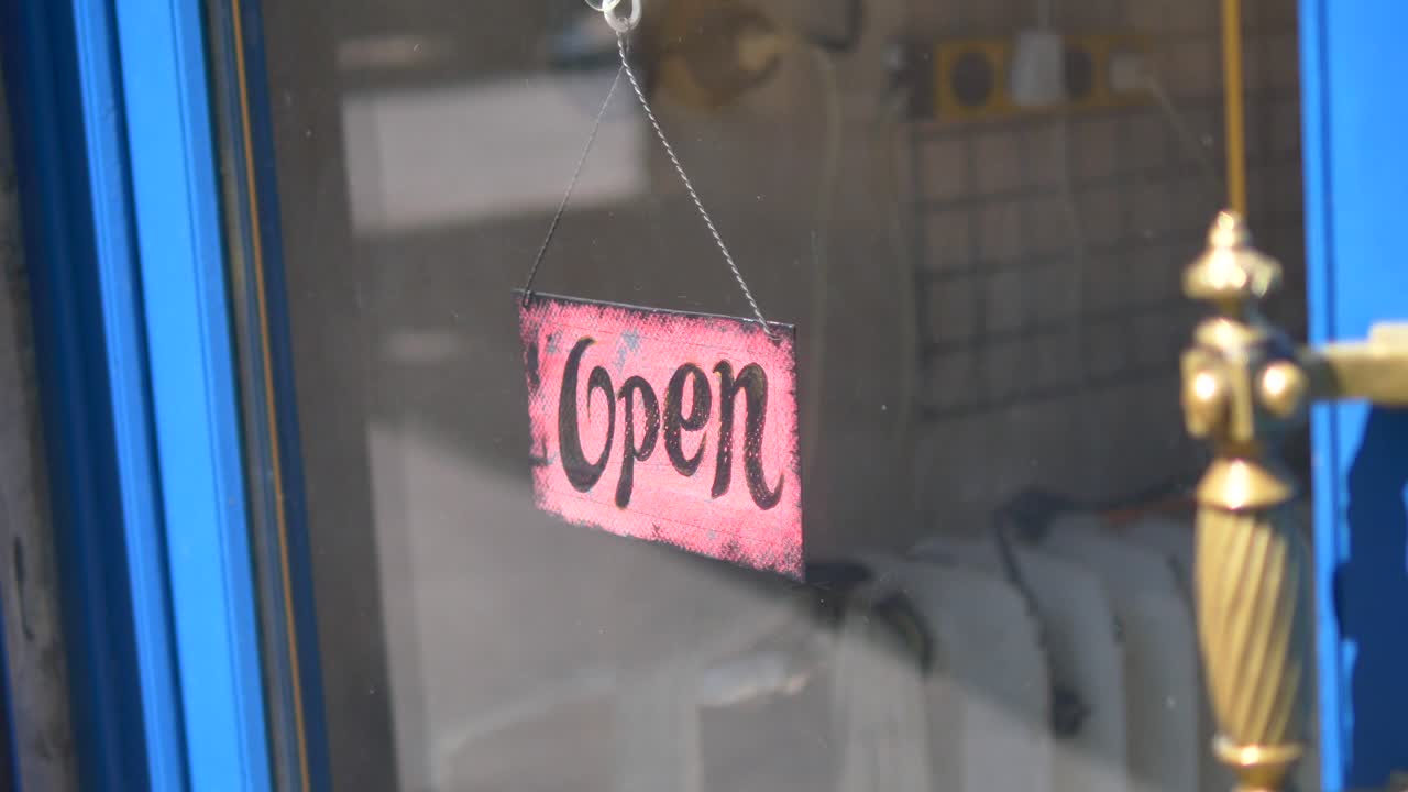 An 'Open' sign hanging in a shop window