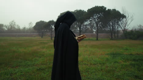anonymous man with mysterious cloak walks reading grotesque book