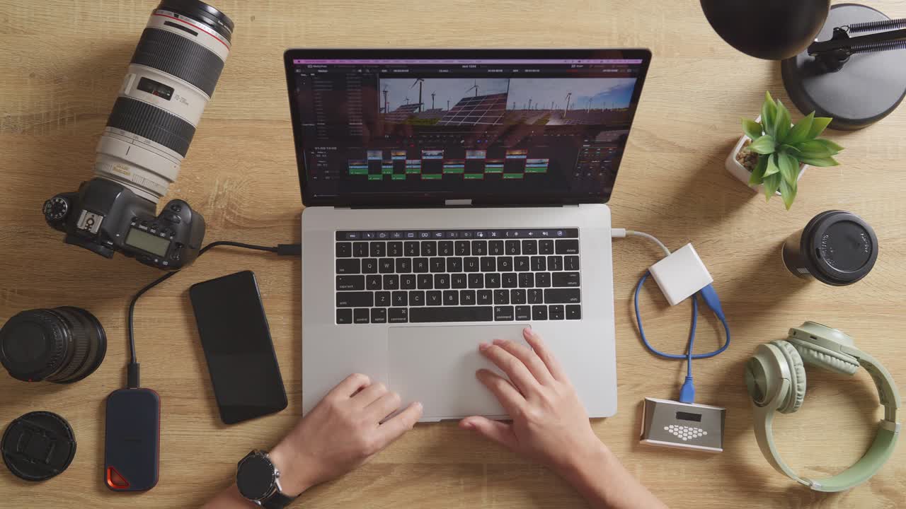 vista superior de cerca de las manos del editor masculino poniendo la tarjeta de memoria en una computadora portátil y luego eligiendo el video en el espacio de trabajo en casa