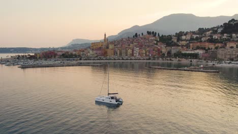 Beautiful-Sunset-with-Yacht-Boat-on-Menton,-France-Coastline---Aerial-Drone-Landscape
