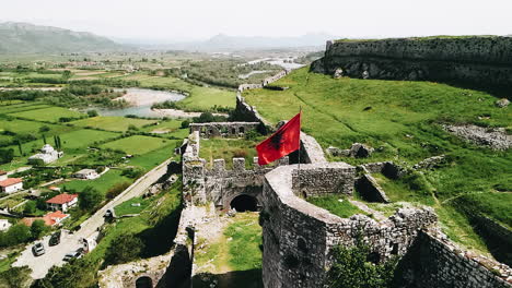 Toma-Aérea-En-Cámara-Lenta-De-La-Bandera-Albanesa-Ondeando-En-El-Viento-En-Las-Ruinas-Del-Castillo