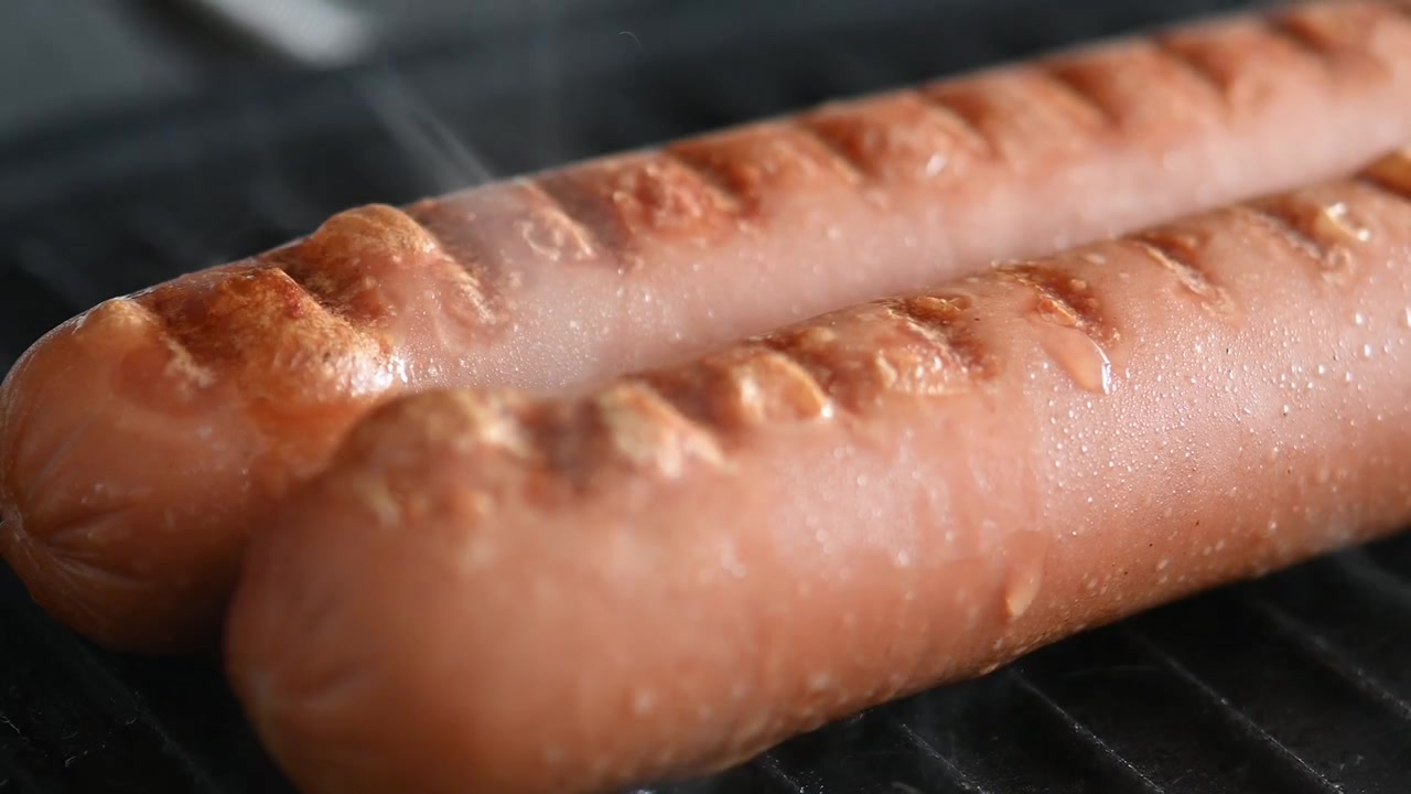 熱いグリルパンでジュージューと焼ける2本のソーセージ。