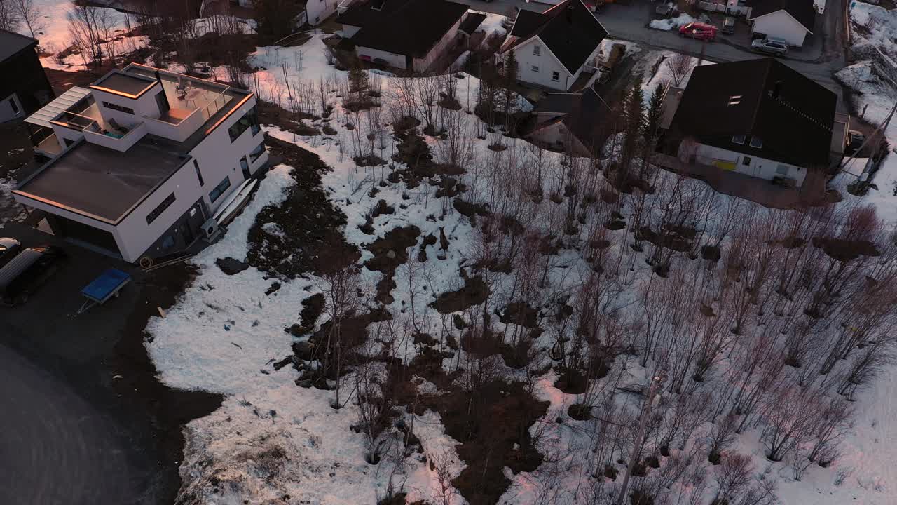 vista aérea de alces caminando en la nieve cerca de las casas durante la puesta de sol