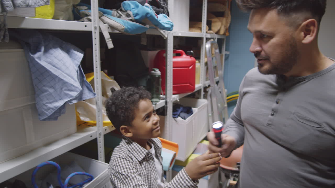 niño de raza mixta ayudando a papá con la preparación de la mochila para acampar