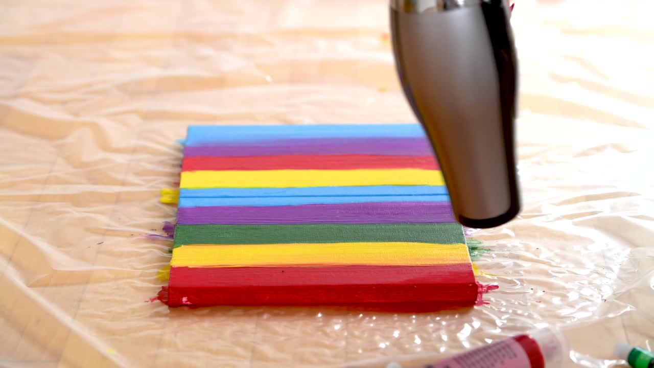 한 여자 가 캔버스 에 있는 다채로운 줄무 의 그림 을 건조 시키고 있다