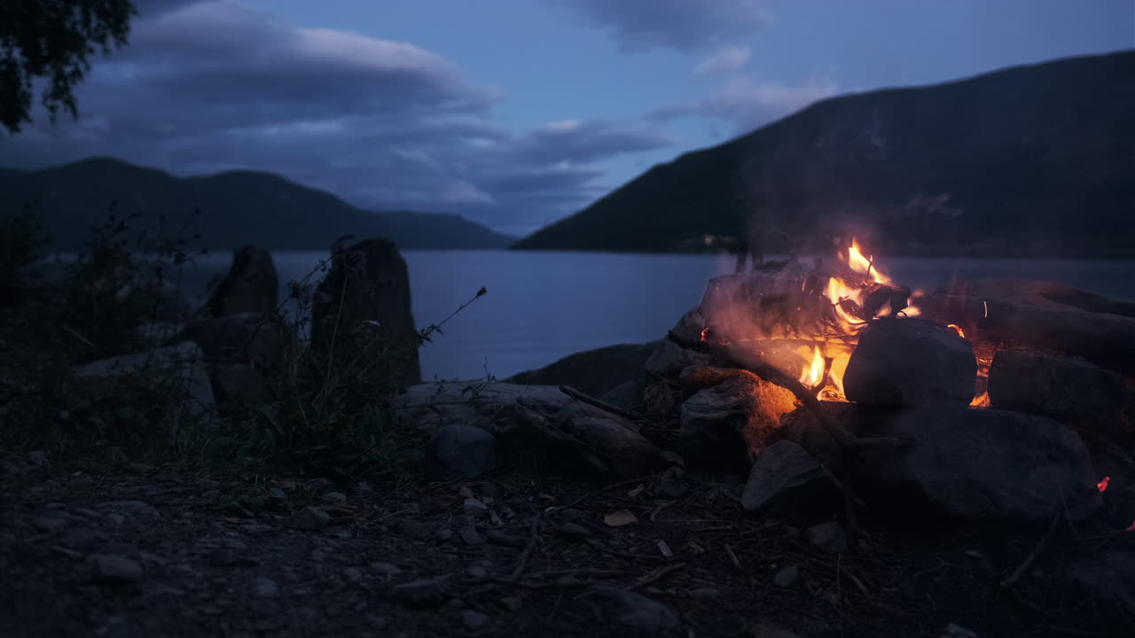 gran hoguera en la playa junto a un lago en noruega en una fiesta nocturna de verano en la naturaleza noruega