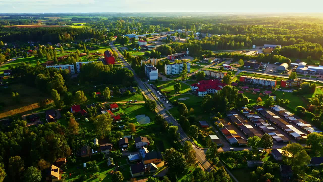 Wide aerial view of Smiltene town during warm sunset with buildings and trees in Latvia