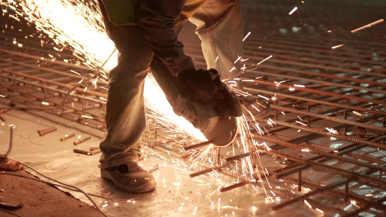 Industrial professional worker is cutting metal rebar with a circular saw. Construction of a factory, hangar