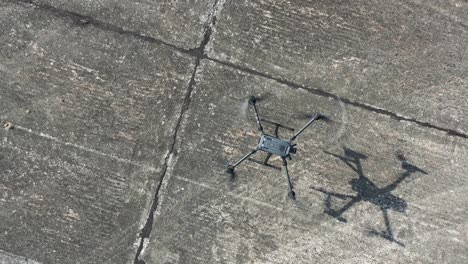 quadcopter drone aircraft landing on concrete sunface, top down aerial view