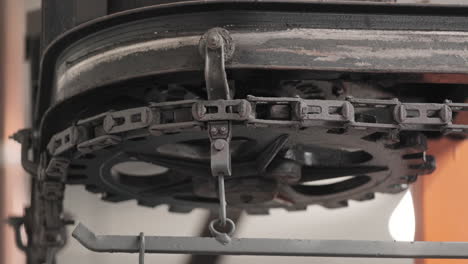 mechanical gear with metal chain rotating slowly in a factory - close up