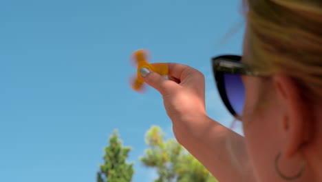 mujer jugando con el girador de inquietud amarillo al aire libre