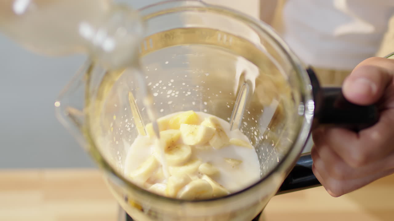 Man Pouring Water in Blender with Fruit for Making Smoothie