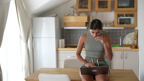 mujer trabajando en una computadora portátil en la cocina