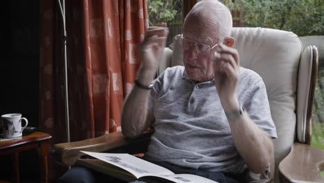 elderly man reading a photo album in an armchair
