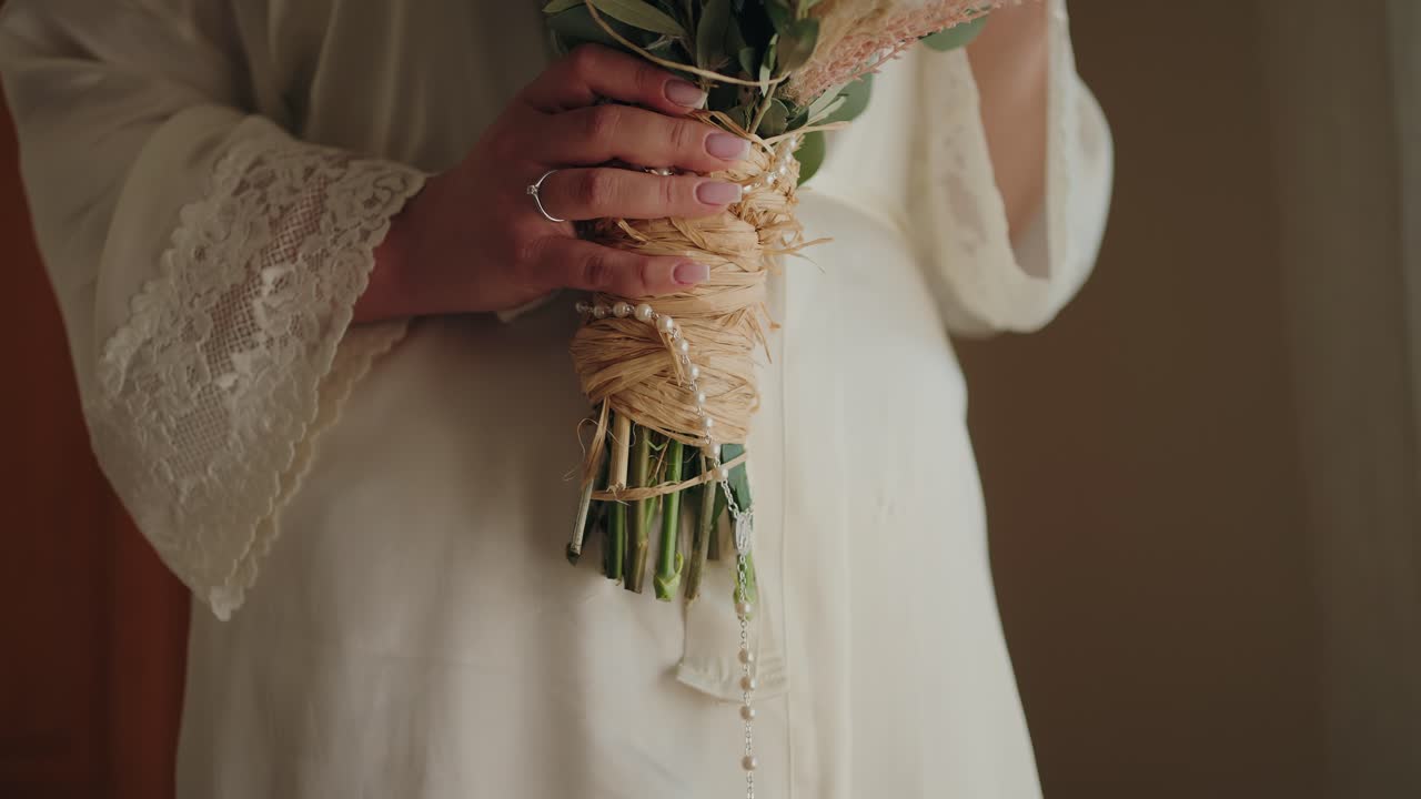 close up of bride holding rustic bouquet with lace robe and delicate engagement ring