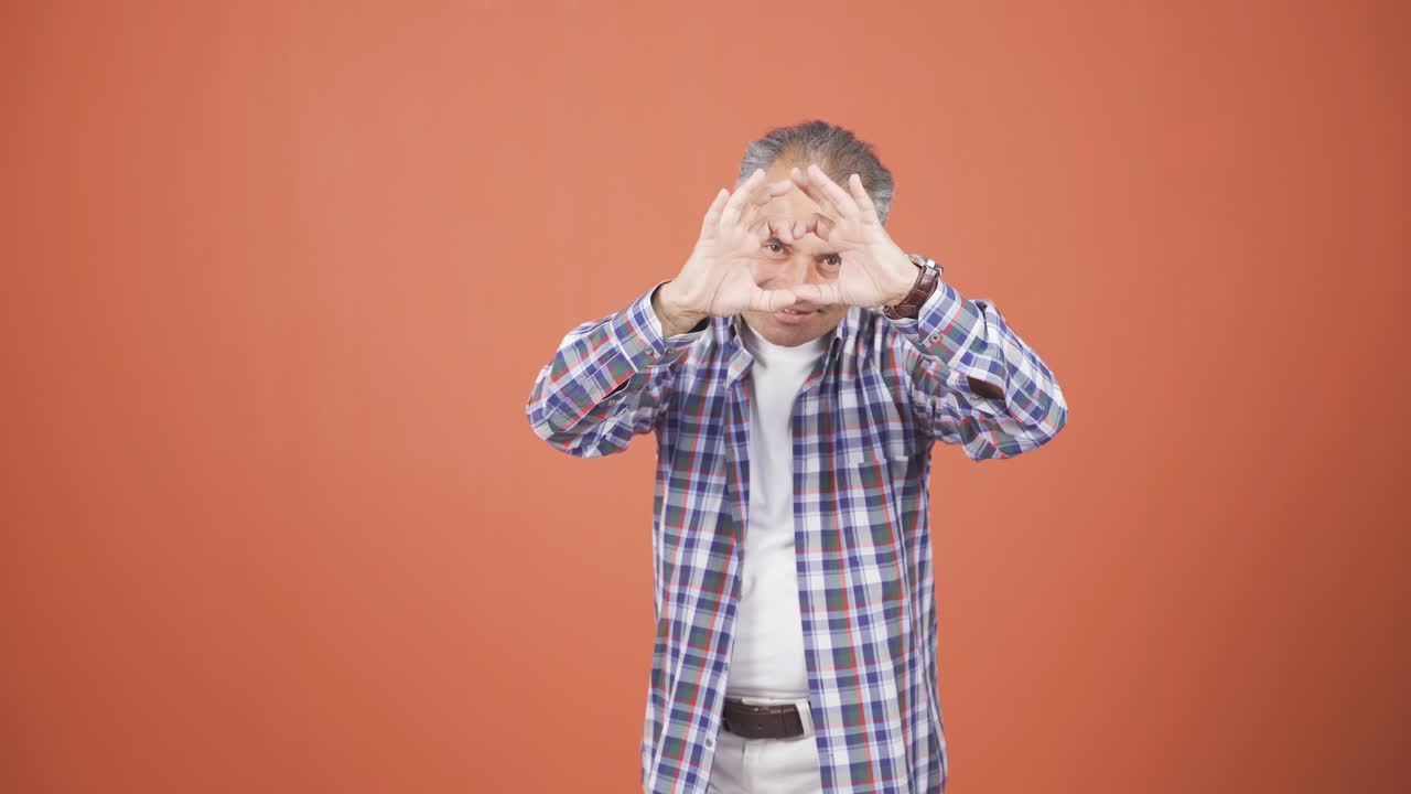 남자가 카메라에 심장 표시를 하고 있습니다.