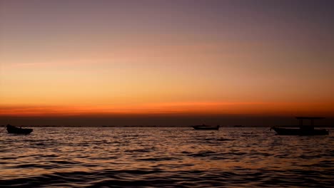 4k. silueta de un pequeño barco sobre el mar con una pequeña ola al atardecer o al amanecer, hermosa luz solar reflejada con la superficie del agua
