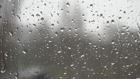 rain drops land on a window and trickle down the glass during a rain storm