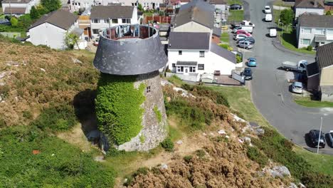 Llangefni-windmill-ivy-covered-sunny-hillside-landmark-aerial-view-circling-above-Welsh-neighbourhood