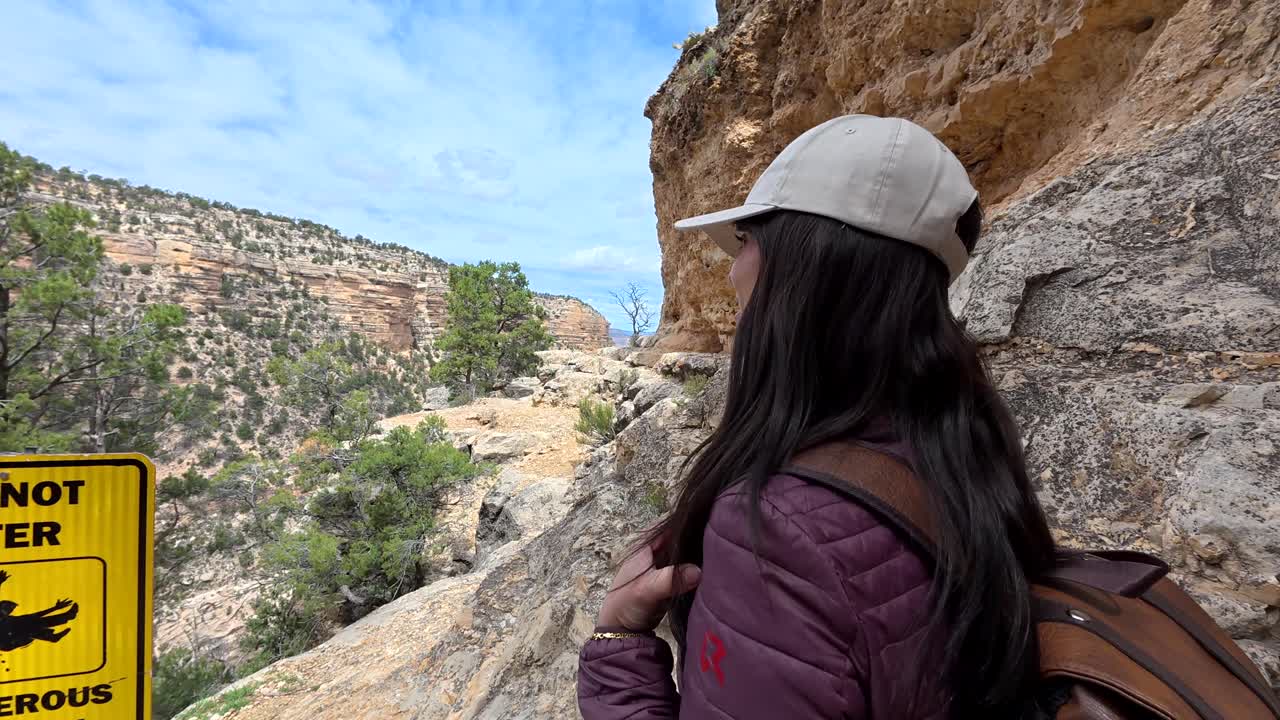 Jovem mulher fazendo trilha em um cânion rochoso.