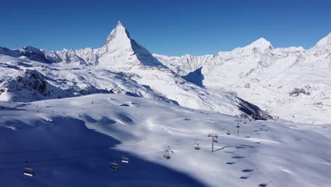 esquiadores en la pista de esquí blanca frente al hermoso matterhorn en suiza, cielo azul