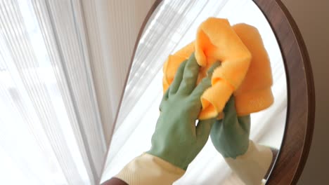 cleaning a mirror with gloves and a cloth