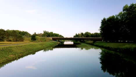 Aerial-view-of-man-riding-bicycle-and-couple-walking-on-canal-trail-near-bridge