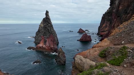 Rock-formation-in-the-middle-of-the-ocean-and-the-sea,-surrounded-by-water-with-the-waves-crashing-on-the-cliffs-in-front-of-it