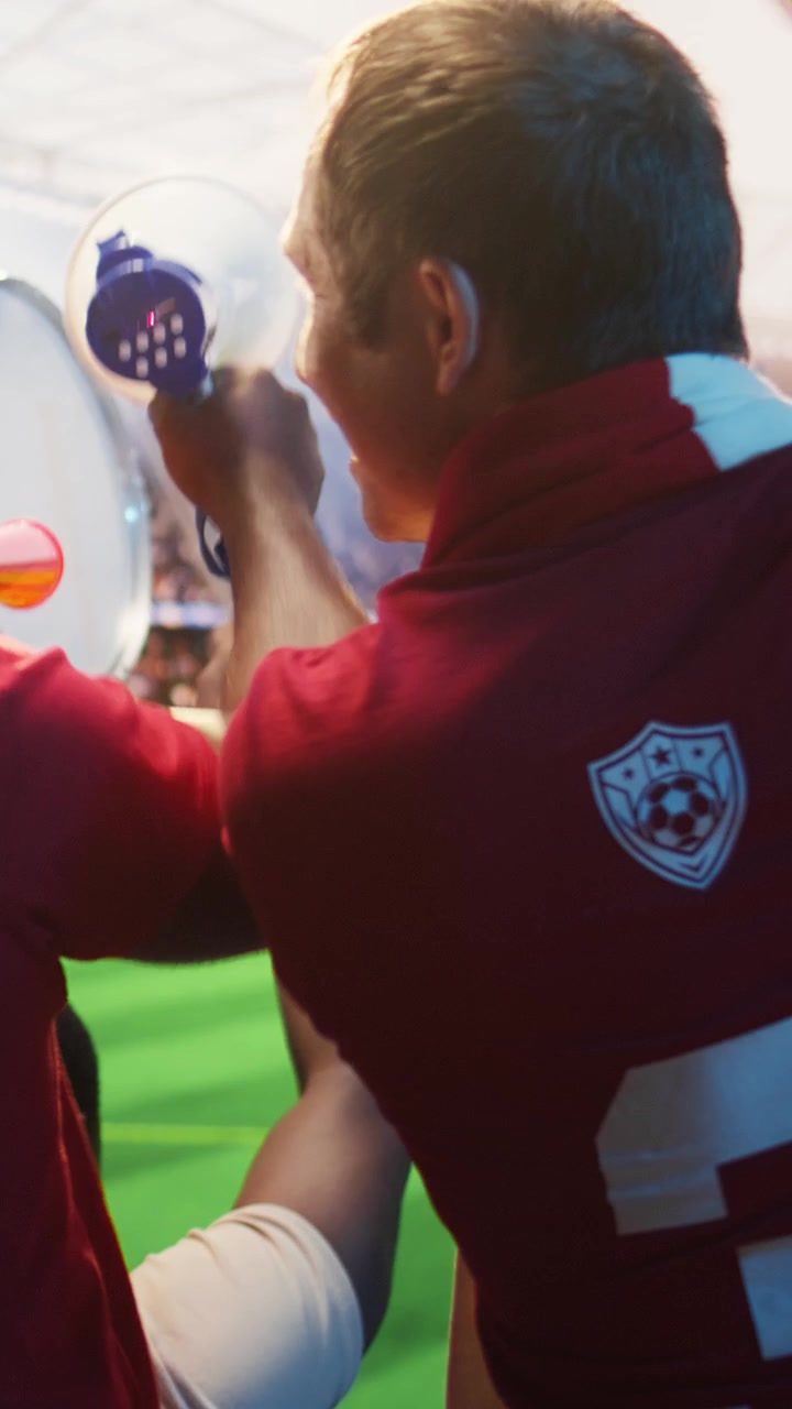 Video verticale. Primo piano di un tifoso di calcio che fa rumore con vuvuzela e trombe ad aria durante la partita.