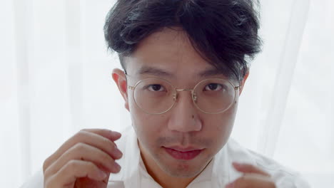 asian man with glasses and healthy good hair looking to the camera and spoiled himself by tidying his hair