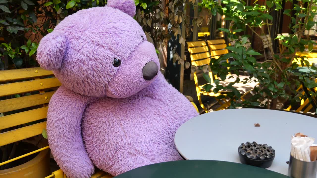 Purple Teddy Bear Sitting in an Outdoor Cafe
