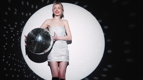 woman in a silver dress holding a disco ball