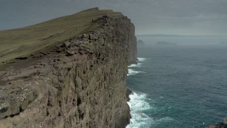 Dramatic-Nature-Scenic-Of-A-Person-In-Distance-Hiking-At-The-Traelanipa-Cliff-Towering-Above-The-Atlantic-Coast-In-Vagar,-Faroe-Islands-In-Denmark