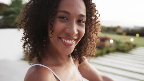 Portrait-of-happy-biracial-woman-smiling-in-garden,-in-slow-motion