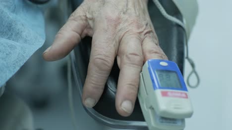 paciente viejo con oxímetro de pulso en el dedo para el monitoreo durante la cirugía en el hospital