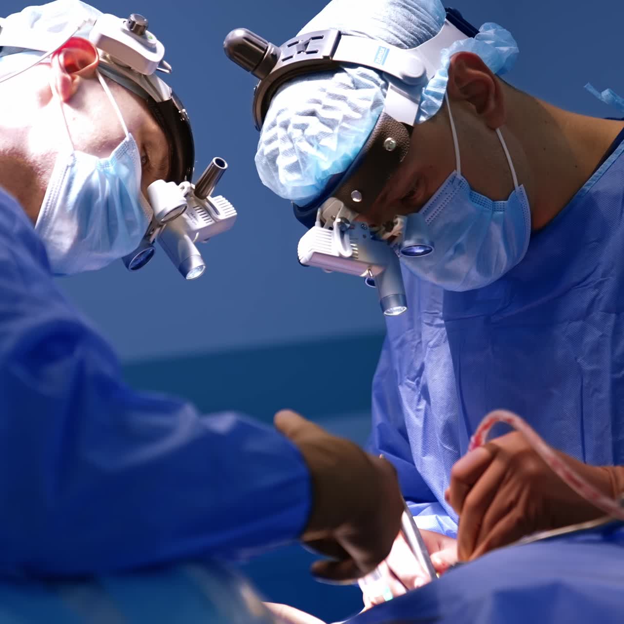 Two neurosurgeons wearing headlights using electric tools. Doctor's cooperation at operational procedure