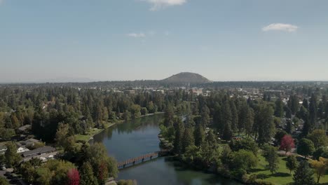 aerial shot over the deschutes river winding through in bend, oregon with a view of pilot butte in the distance