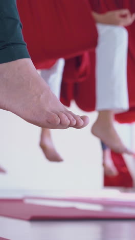 motion along ladies slim legs in leggings with bare feet practicing butterfly fly yoga pose low angle shot close view