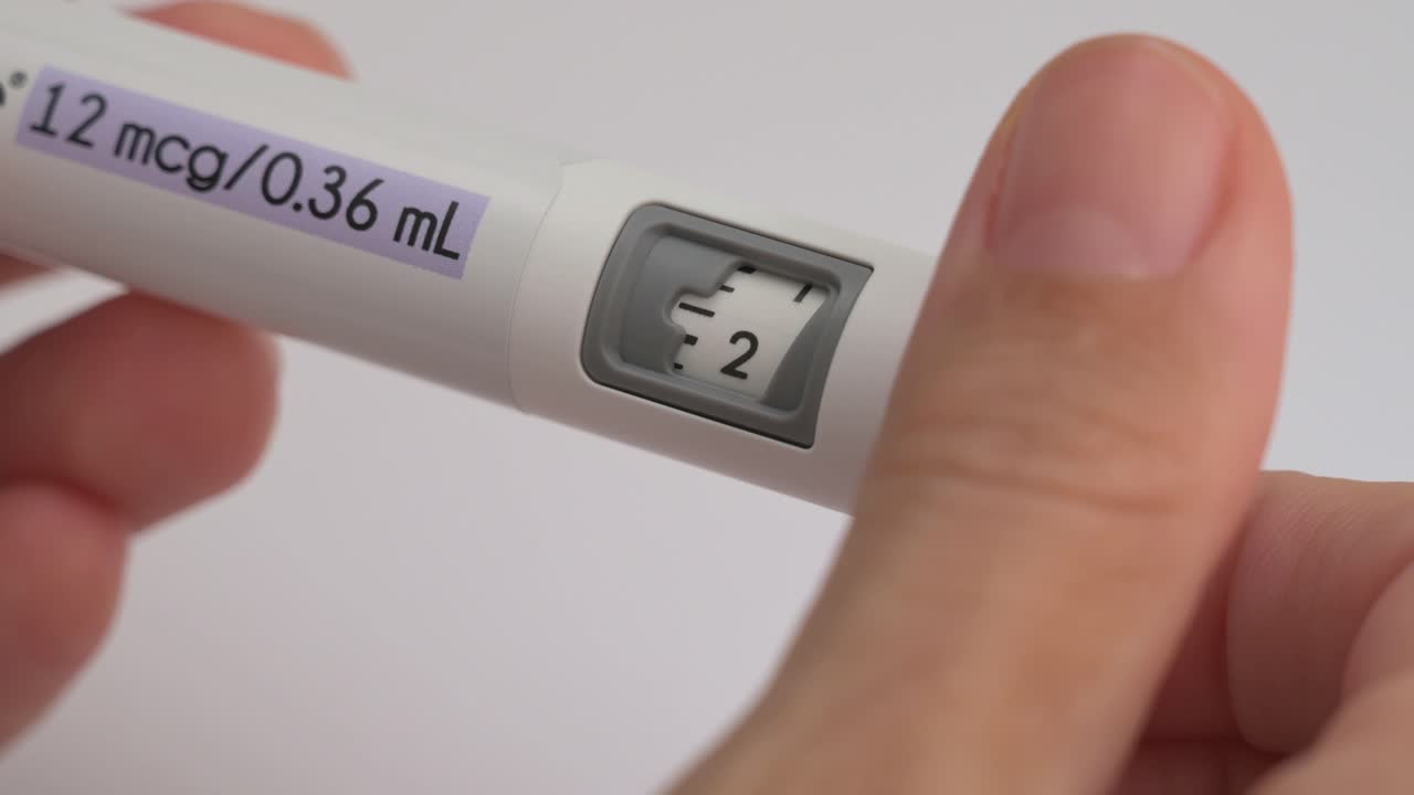 Person dialing the dose on an injection pen for IVF hormone therapy on a white background