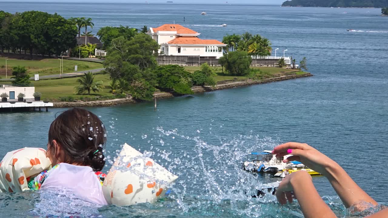 Female Tourist Having Fun With Young Daughter In Swimming Pool By The Sea At Marriott Hotel In Kota Kinabalu, Sabah, Malaysia. closeup, rear shot