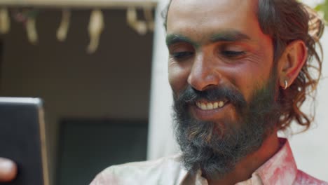 indian man close-up of face smeared with bright holi colors