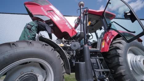 farmer mechanic repairing tractor. open tractor hood, engine. repair agricultural technology