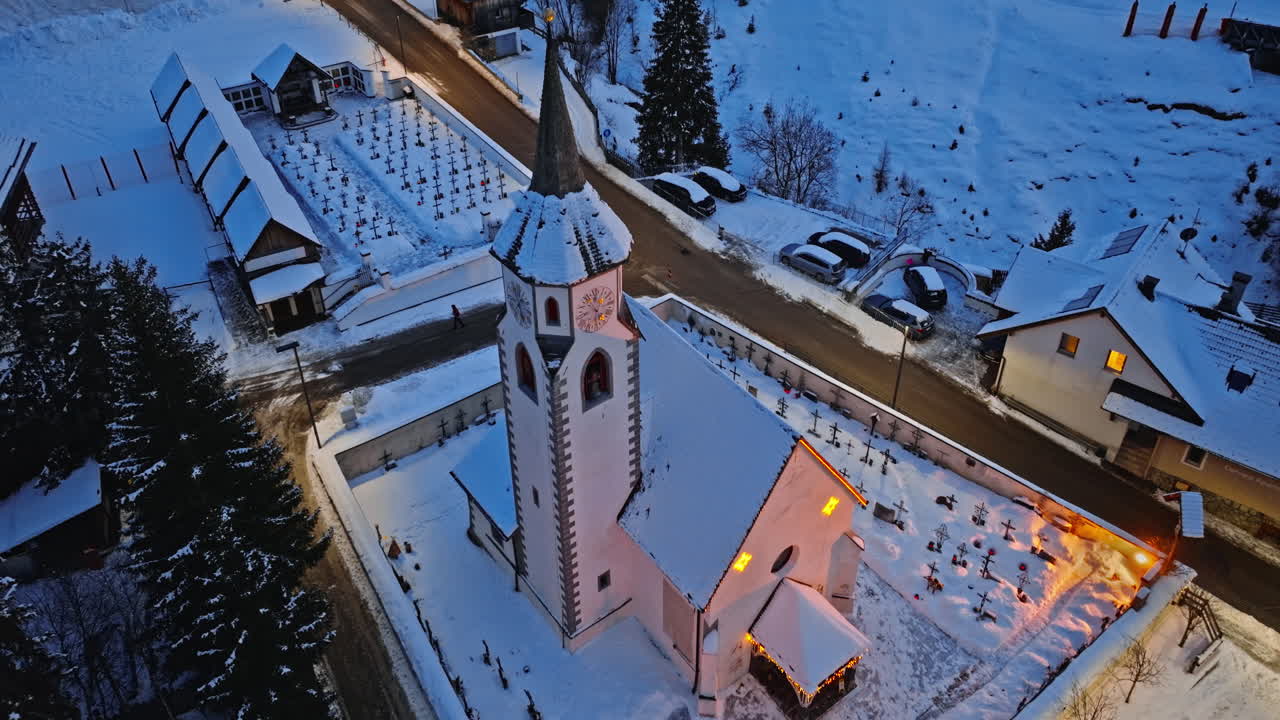 Letecký pohled dronem na vesnici Corvara pokrytou sněhem během modré hodiny, v Jižním Tyrolsku, Dolomitech, v severní Itálii