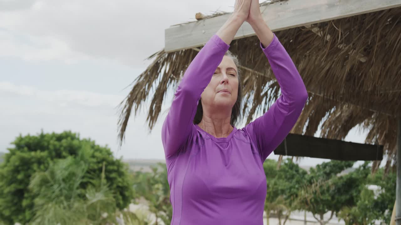 mujer caucásica mayor feliz practicando meditación de yoga en la playa, en cámara lenta